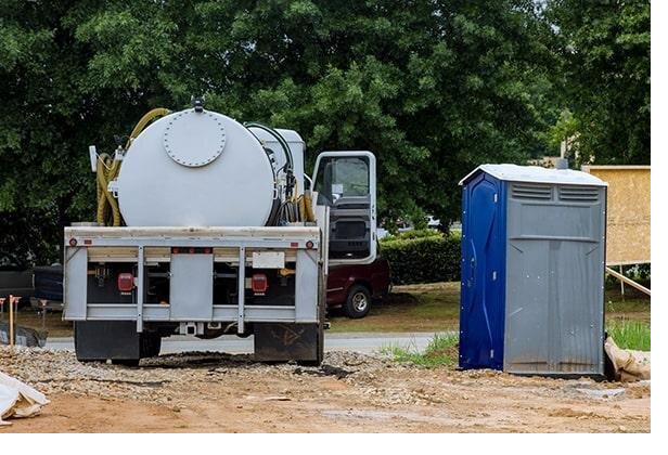Service technician pumping out and servicing a portable restroom unit